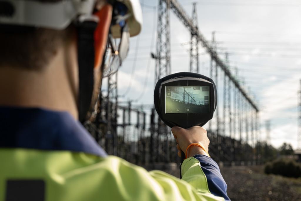 Man pointing an acoustic camera at power lines at an electrical substation.